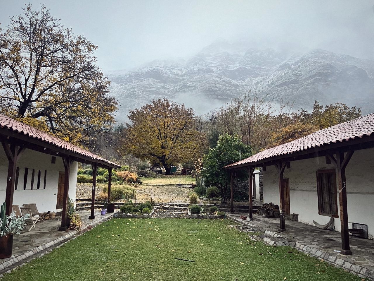 Casa de campo con corredores y cordillera nevada entre la niebla